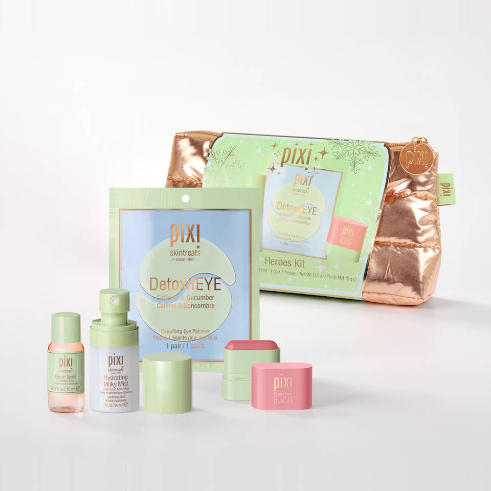 Pixi Heroes Kit skincare set on a clean white background, featuring a metallic rose gold zippered pouch, a light green sachet, a small pink jar, a light green bottle, and other matching skincare containers. view 2
