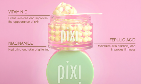 Pixi Vitamin C CremeSerum jar with a mint green cap and clear jar showing yellow serum, set against a solid pink background with text detailing the ingredients.
