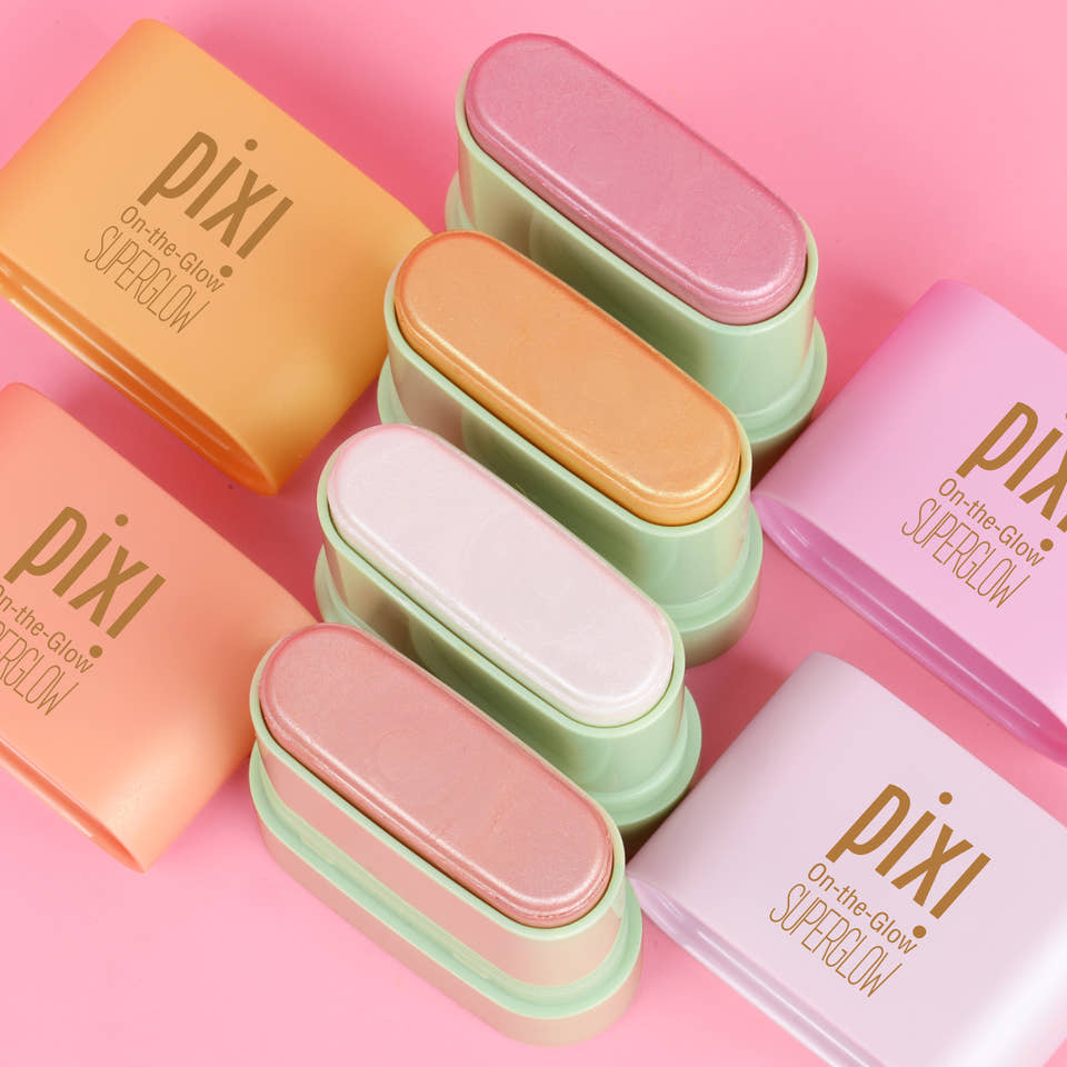 Six Pixi contour and highlight sticks in pastel shades of orange, peach, pink, mint green, white, and lavender, arranged diagonally on a solid pink background. view 2