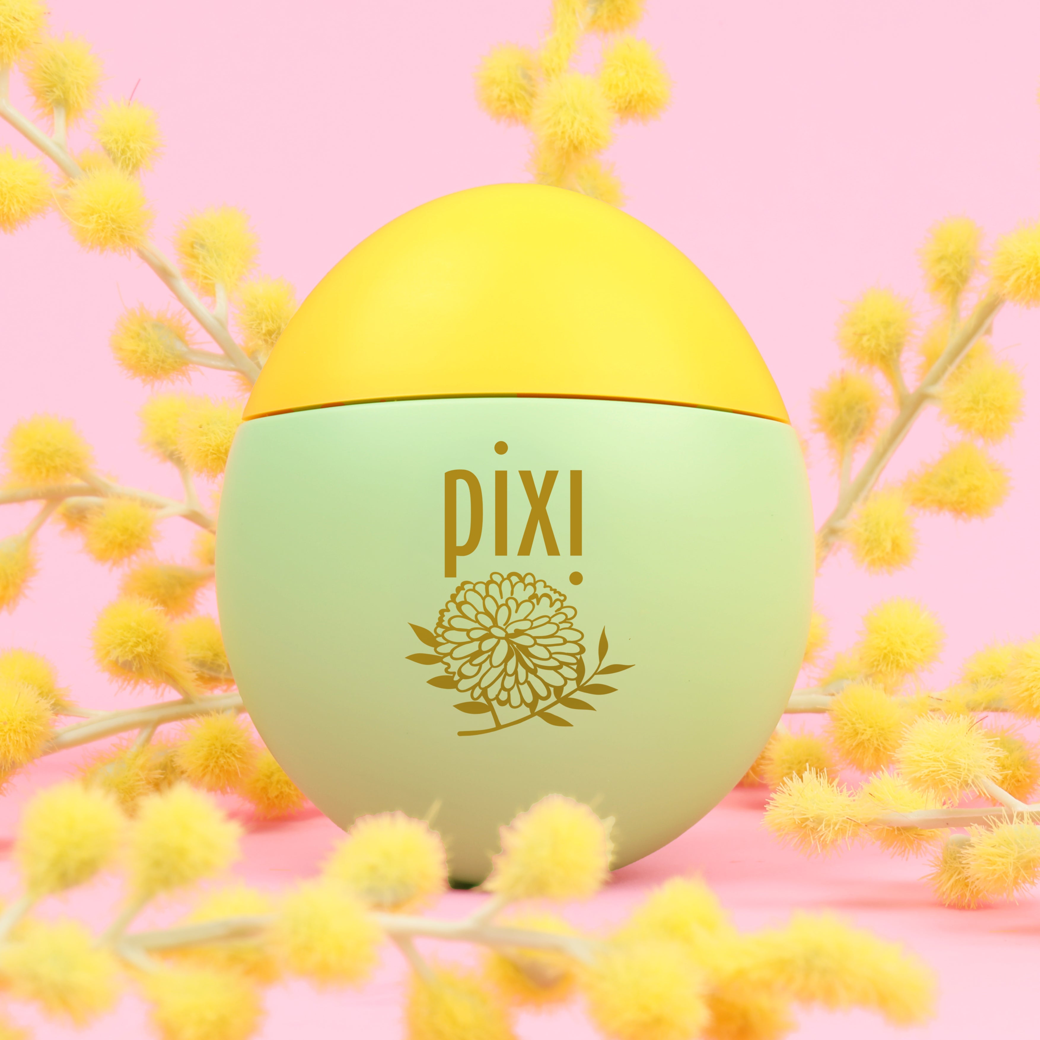 Pixi HandHero PixiMimosa scented hand lotion with mimosa blooms on a pink background