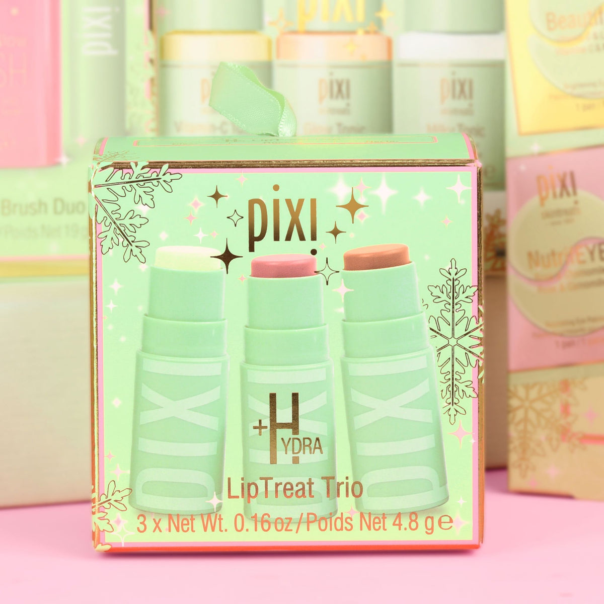 Pixi +Hydra LipTreat Trio in a decorative mint green box with pink glitter accents, showing three lip balm sticks in pale green, pink, and peach tones.